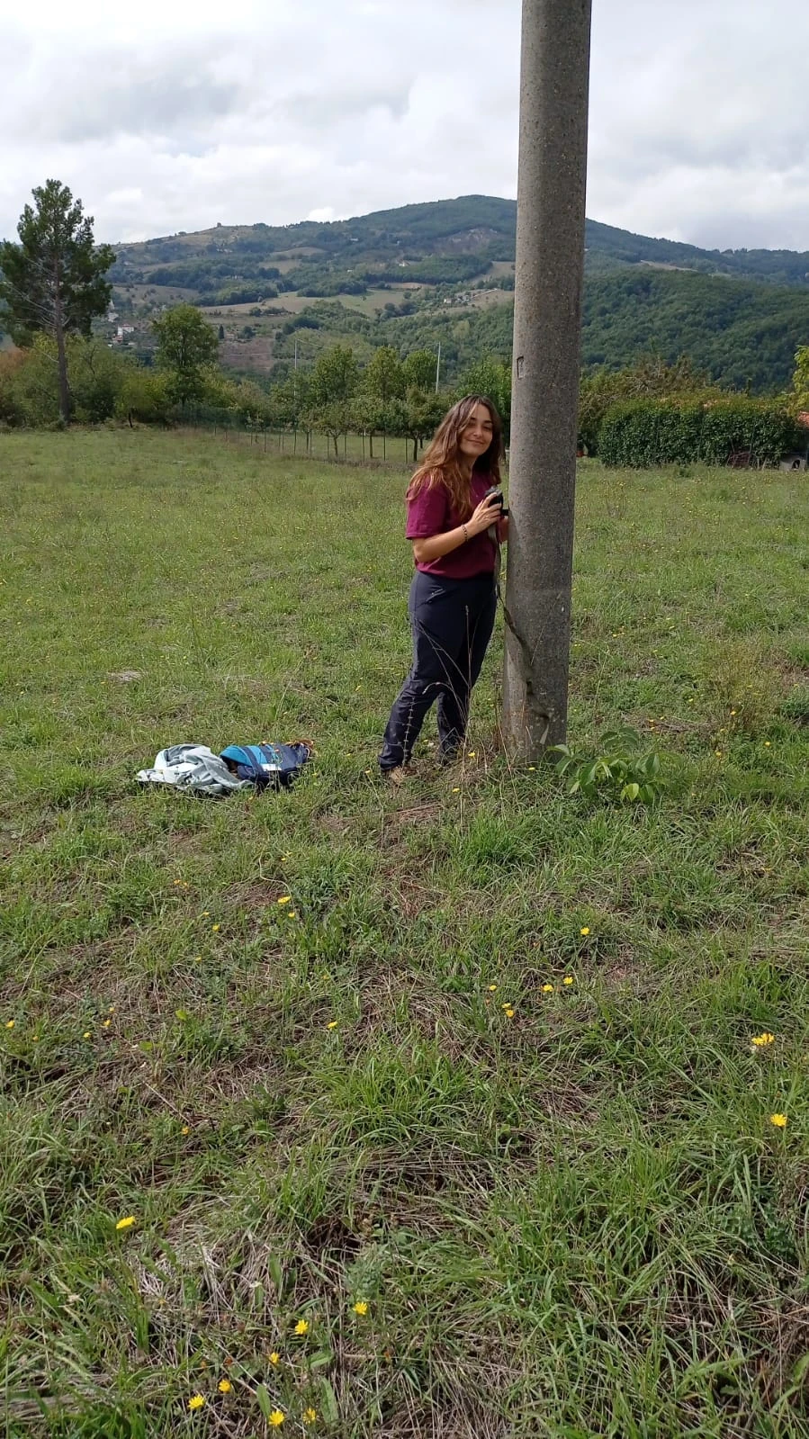 Laura beside a monitoring site in a grassy landscape